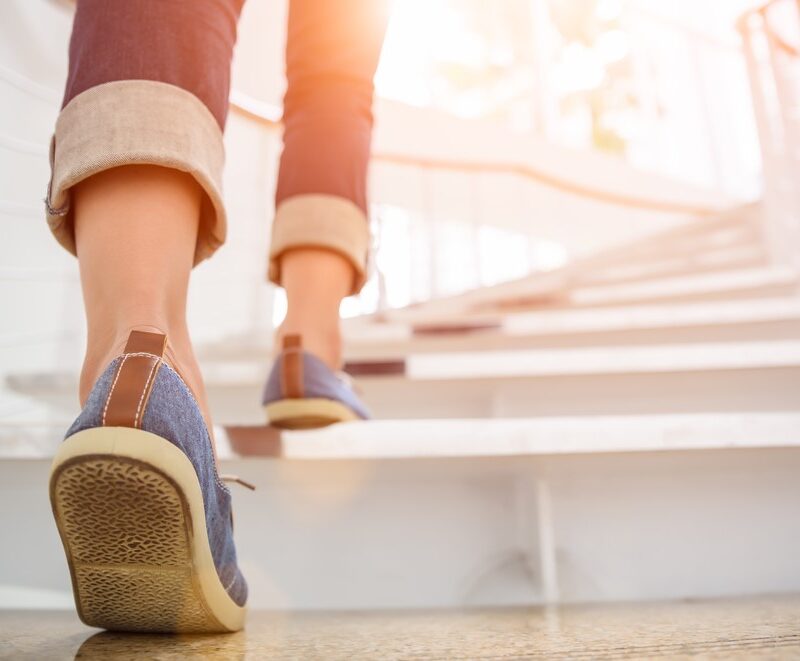 Young adult woman walking up the stairs with sun sport background