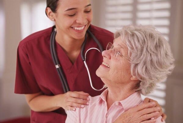 Female nurse looking and smiling with senior Caucasian woman at a rest home
