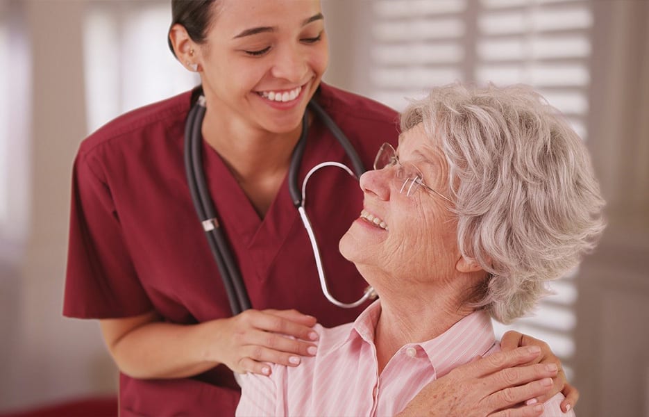 Female nurse looking and smiling with senior Caucasian woman at a rest home