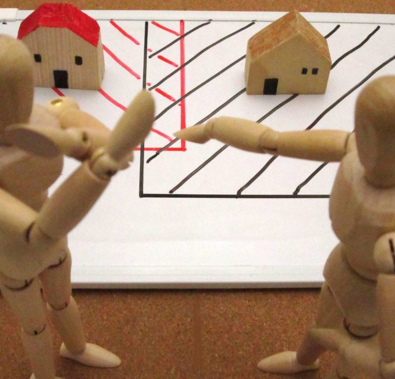 Two wooden people fighting over property boundary