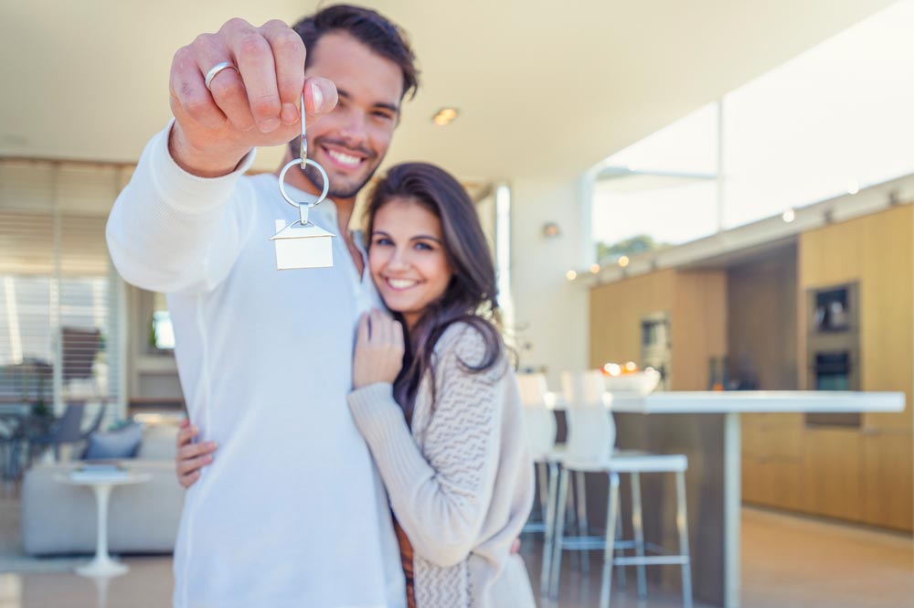 couple standing in new house with keys