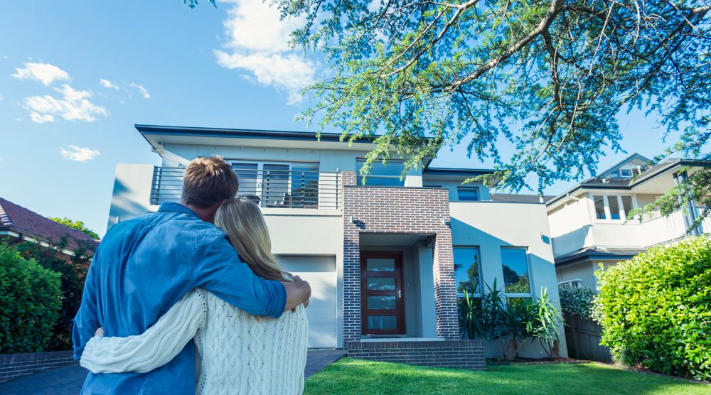 couple standing in front of new house admiring it