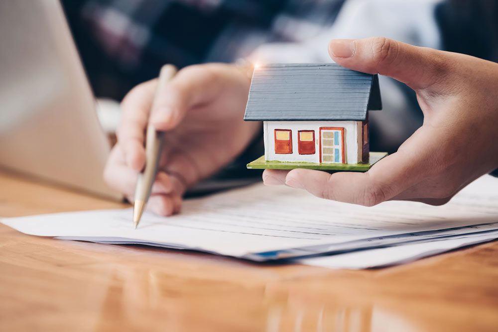 mini house being held and papers being signed